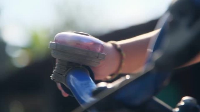 一个孩子的手在公园的自行车车把上敲响自行车铃的特写镜头。