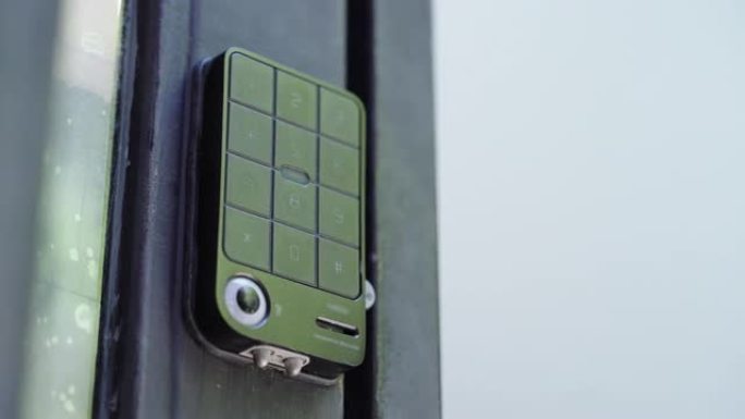 一只手按下公寓电子门锁键盘上的安全码并进入