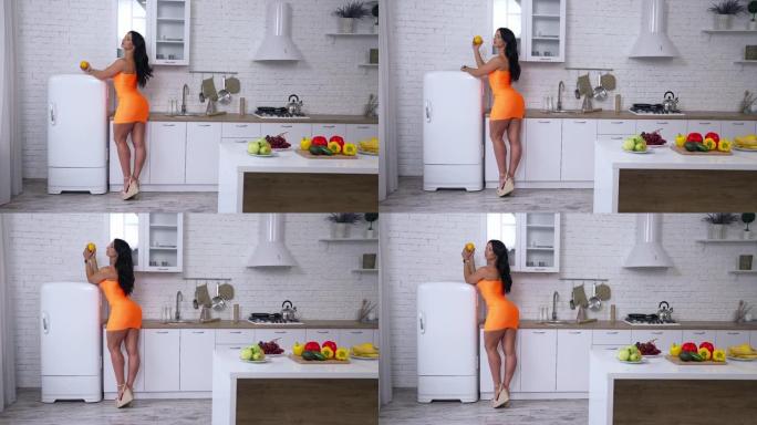 自信的黑发女人站在冰箱旁，在厨房准备早餐。库存照片