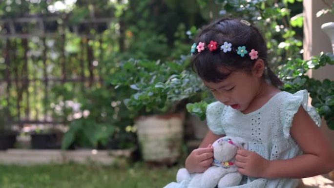 可爱的泰国女孩子，头带花，在花园里玩玩具
