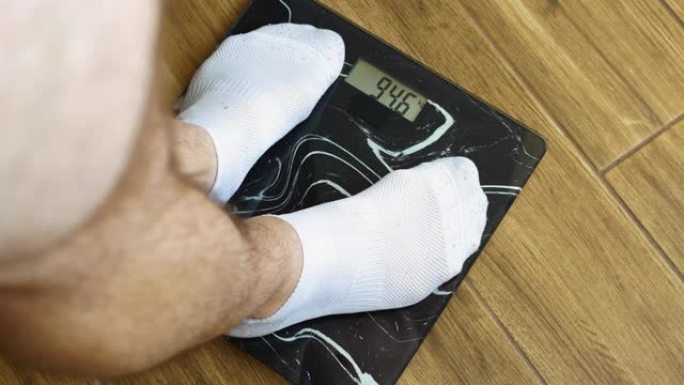 人的体重控制，男性的腿在白袜站在地磅，95.6千克人，肥胖和超重在一个人