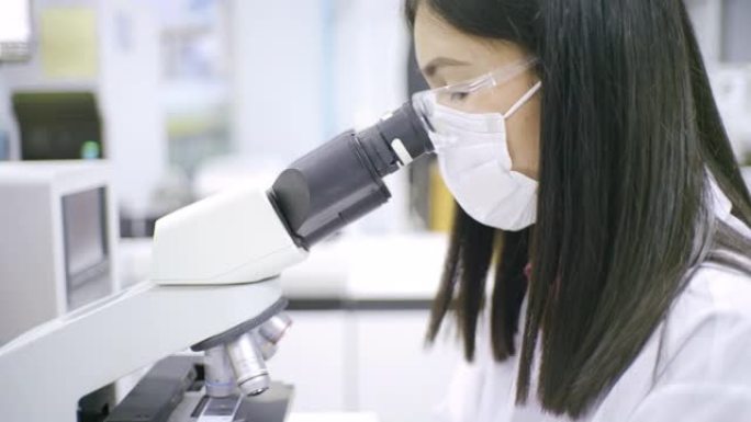 医疗技术人员，在血液实验室使用显微镜。