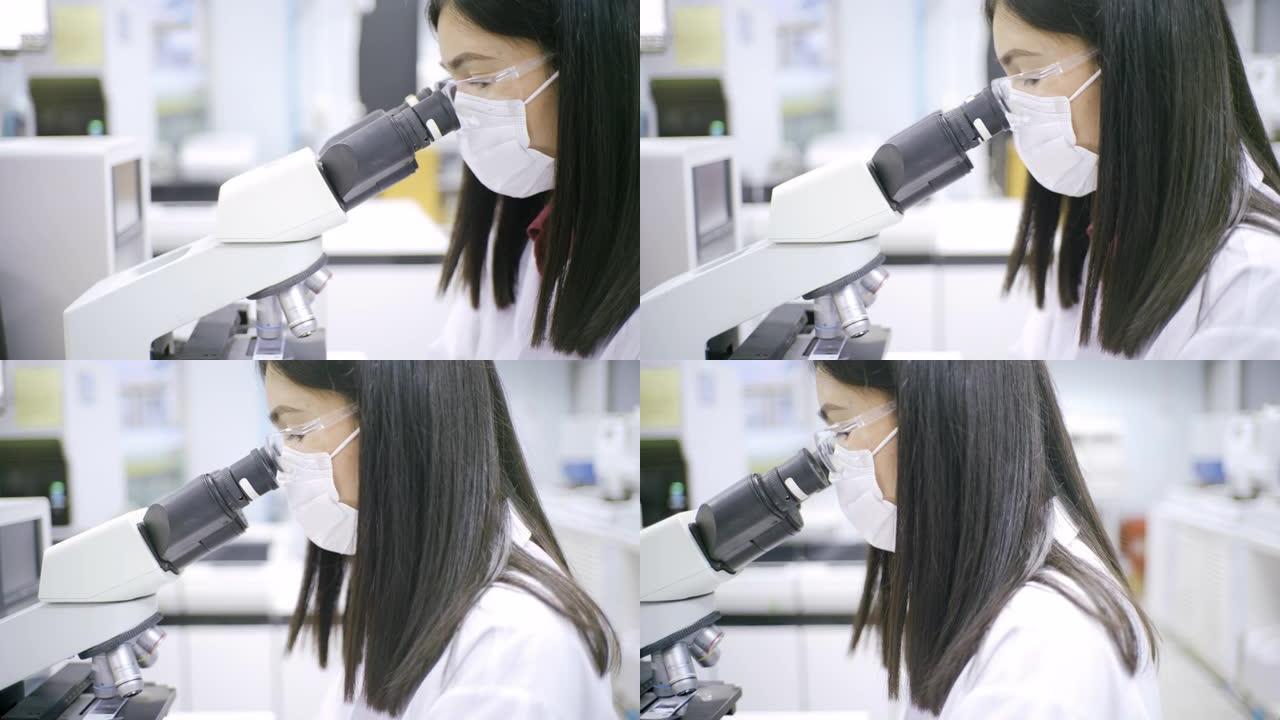 医疗技术人员，在血液实验室使用显微镜。