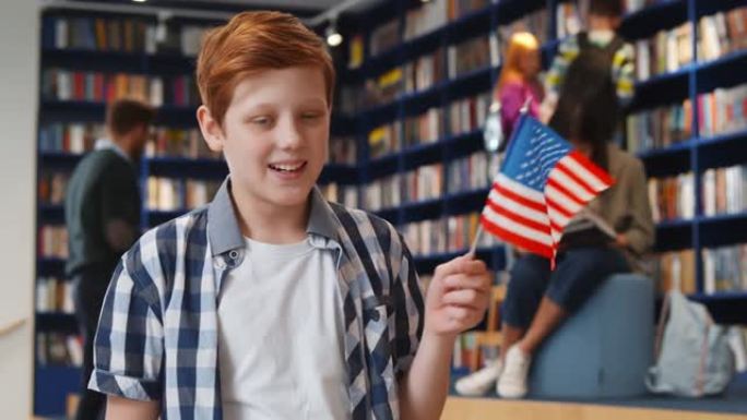 在公立学校图书馆中举着美国国旗的青春期男孩的肖像