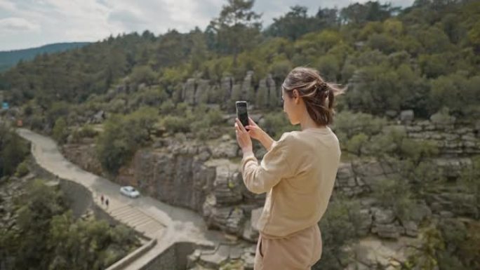 科普鲁峡谷悬崖边缘的女游客徒步旅行者获得全景照片。Koprulu峡谷是土耳其常见的旅游胜地。女孩用手