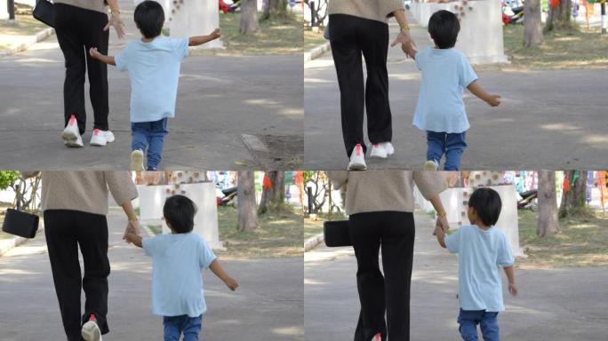 亚洲母子在人行道上手拉手行走。