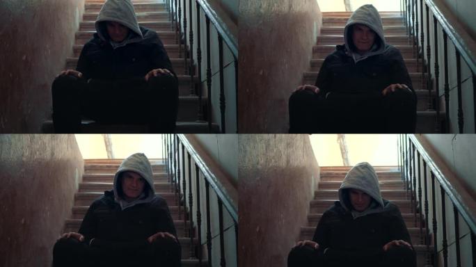孤独的人低着头坐在黑暗中的楼梯上。压力和抑郁心理问题概念