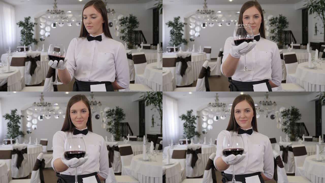 一个年轻的女侍酒师拿着一杯红酒的特写镜头。