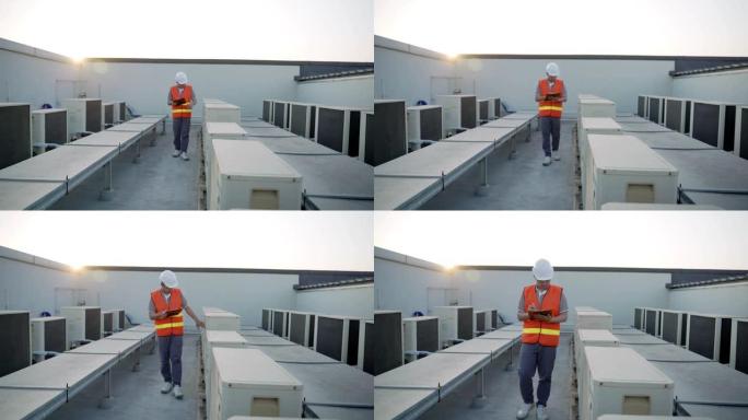 工头行走复检制冷系统工厂及系统运行情况。承包商在工厂的屋顶甲板上记录空调系统。