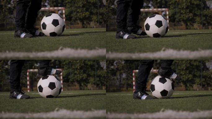 在草地上的一个足球特写镜头，一个男孩把脚放在球上