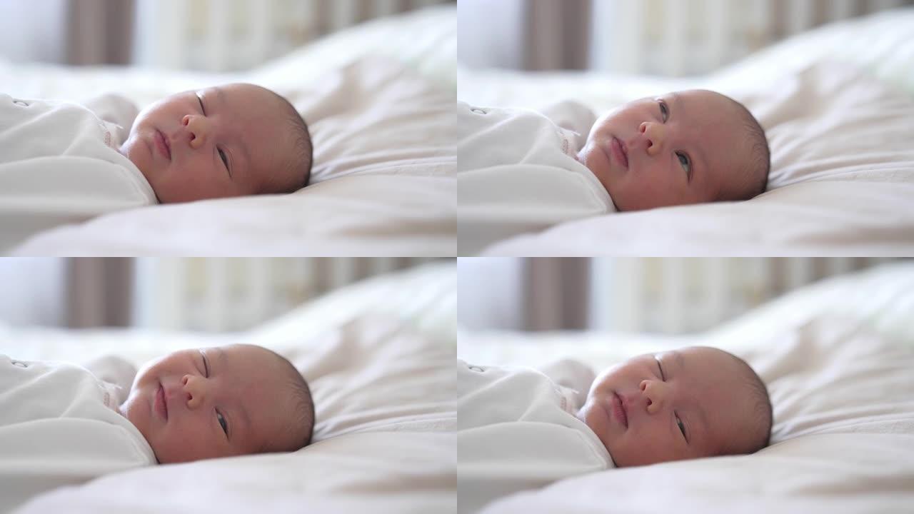 婴儿睡在床上。婴儿在做梦时睁开眼睛，微微一笑。漂亮婴儿脸上的情绪。