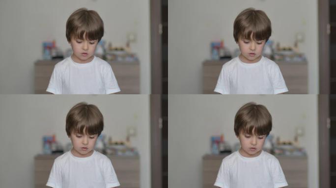 肖像小男孩看着相机。年轻的悲伤思维好奇的孩子在室内看着相机特写。脸眼睛严肃沉思的孩子特写。体贴的小男