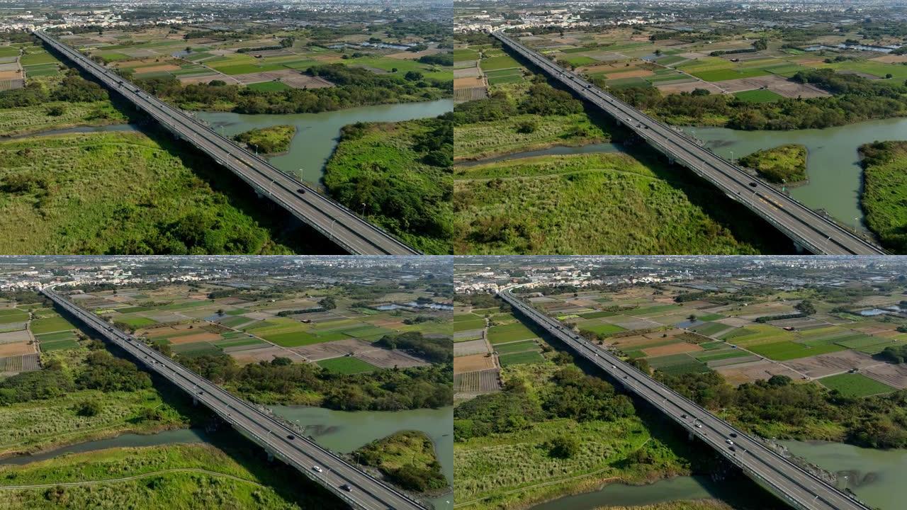在高速公路路口行驶的汽车的鸟瞰图。连接建筑概念的绿色花园和树木的桥梁道路。
