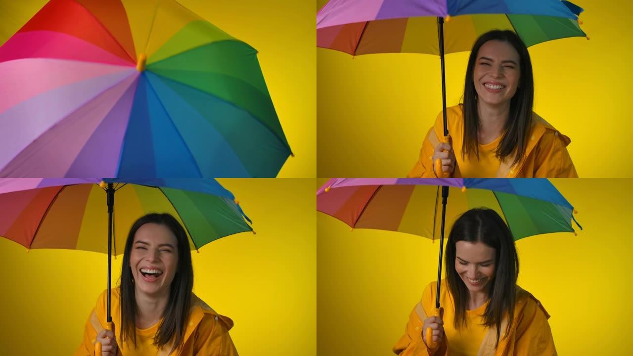 穿着黄色雨衣的开朗女人转彩虹伞笑