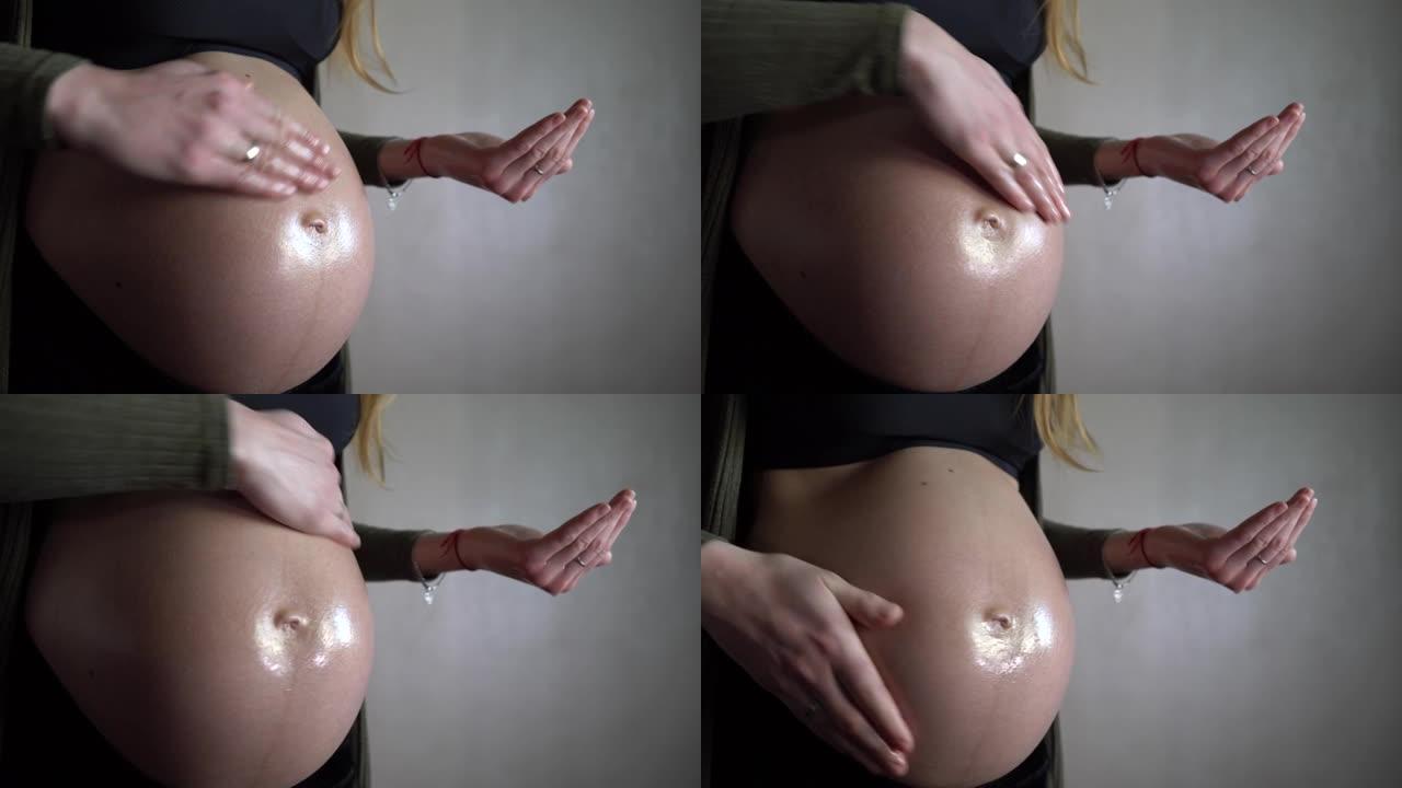 孕妇使用油乳液和摩擦腹部。特写。
