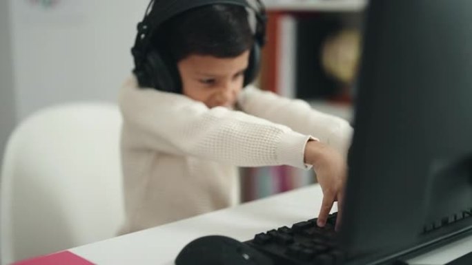 可爱的西班牙裔男孩学生使用计算机坐在教室的桌子上