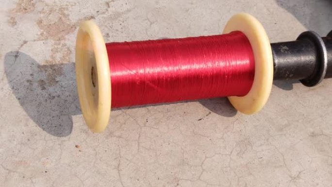 一种红色丝线缠绕在由手工织布机引导的线轴上，用于纺织品生产。用纺车或Charkhi从卷轴上取出线。手