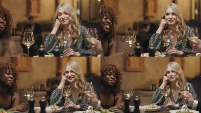 晚上在友好聚会上在餐厅餐桌上的金发女人的肖像，同学聚会