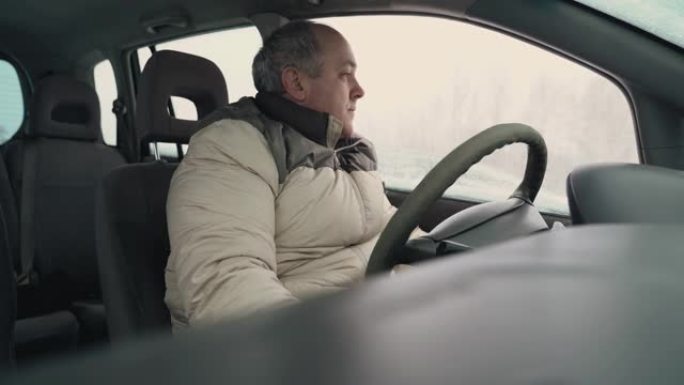 疲惫的男司机在冬天打开了汽车的挡风玻璃。