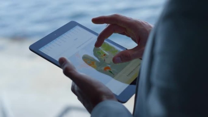 经理在海上景观特写处刷平板电脑。老板分析图表
