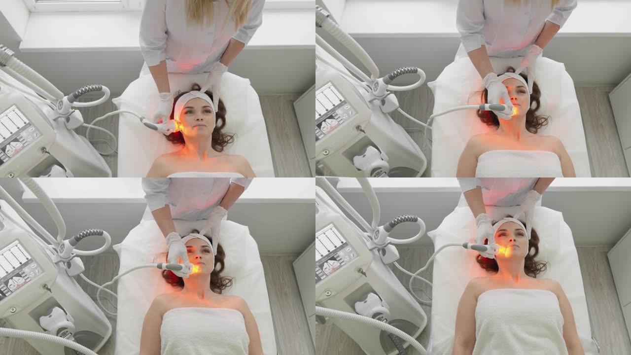 红色LED治疗。做面部皮肤治疗的女人。射频瘦脸。硬件抗老化程序。射频提升和真空按摩。美容师执行美容程