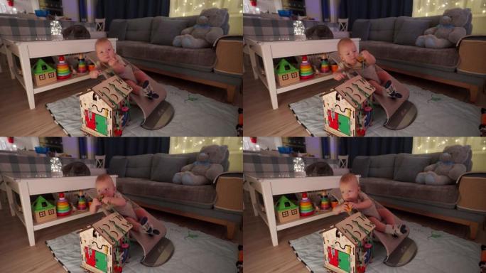 可爱的婴儿坐在婴儿保镖里，10个月大的高加索孩子在家玩木制繁忙的蒙特梭利教育玩具。儿童忙板。