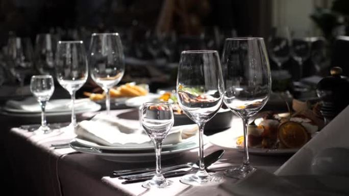 节日的盘子，桌子上的玻璃杯，桌子上的阳光。美丽的婚礼餐桌装饰。婚礼或公司活动中的餐桌庆祝装饰。在阳光