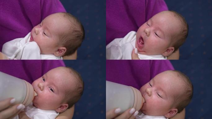 妈妈手里的小孩张开嘴等待瓶子。妈妈给了他一个奶瓶，婴儿饥饿地拿着它，慢慢吃东西，然后闭上眼睛。特写。