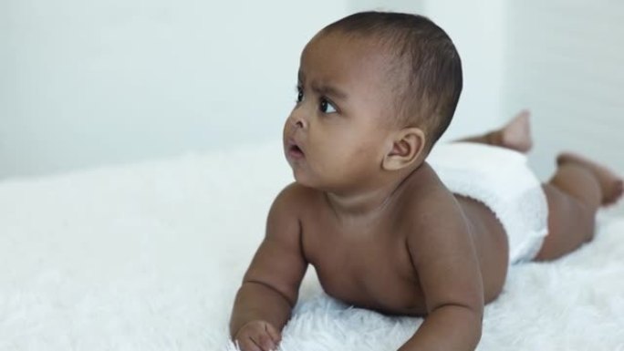 脱衣服的非洲裔美国婴儿在家里的房间里有面部表情。婴儿生长。儿童身体发育的运动。关爱儿童健康健康。幼儿