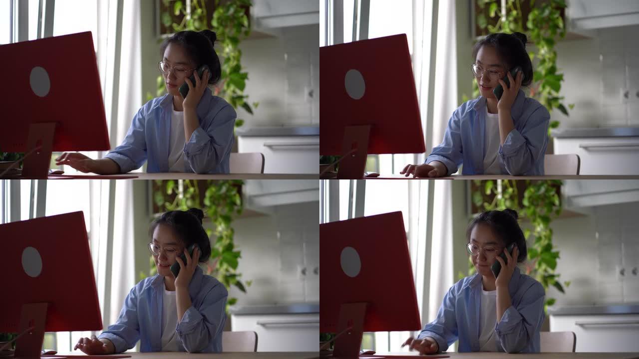 韩国女孩远程员工在家里用电脑工作时打电话