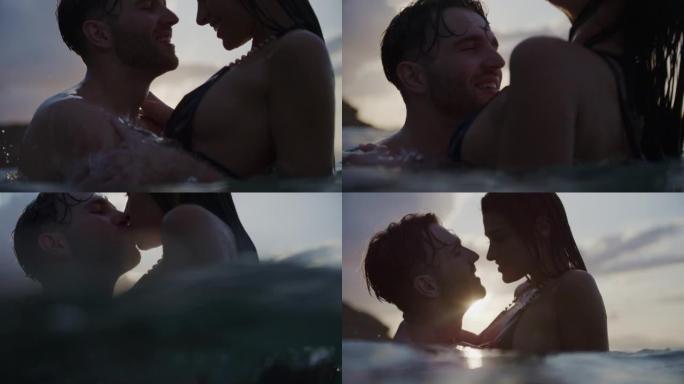 浪漫的异性恋夫妇在美丽的金色日落时在海里游泳。接吻