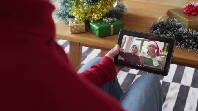 白化病男子挥舞并使用平板电脑与屏幕上微笑的家人进行圣诞节视频通话