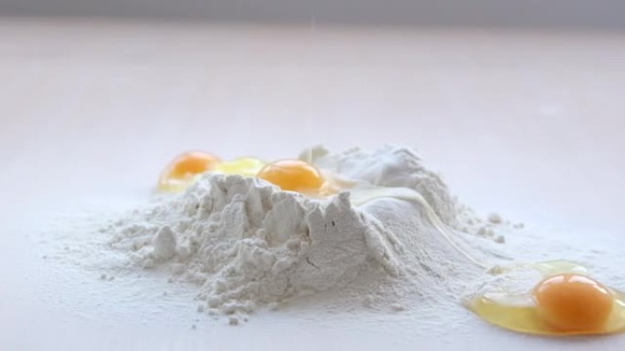 烘焙烹饪美味的烹饪甜点鸡蛋被扔进面粉中，它们失败了，并向侧面滚动视频开始于一个鸡蛋从面粉火山中慢慢滚