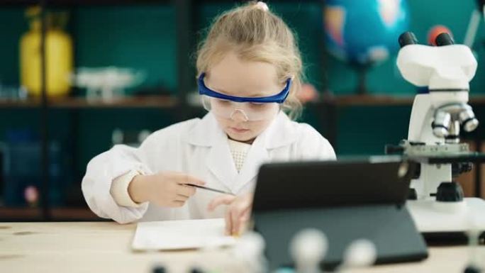 可爱的金发女学生在实验室教室用触摸板在笔记本上写字