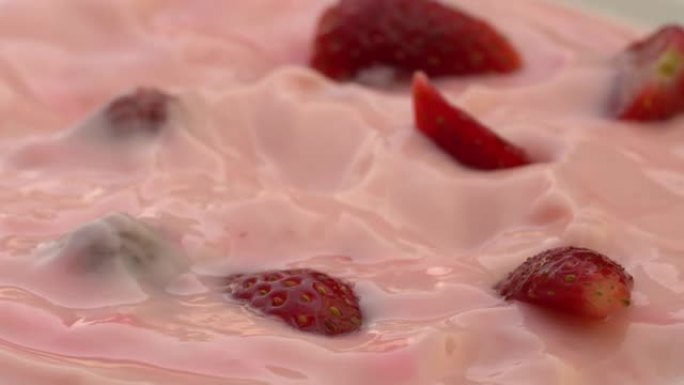 草莓碎片落入草莓酸奶中。