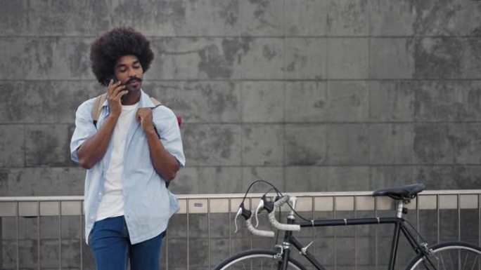 年轻的非洲裔美国男子在老式自行车旁边用手机聊天，与朋友交谈