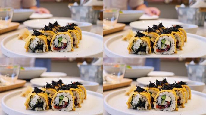 在一家日本餐厅的盘子上滚动的电影镜头。美味的日本菜肴，新鲜的海鲜和蔬菜，酱油和芥末，给面包卷带来更明