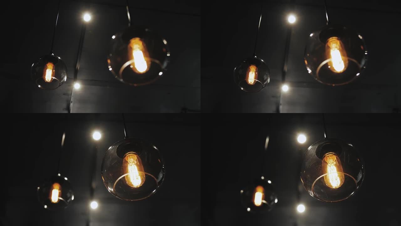 灯罩和老式灯泡在孤立的黑暗房间。特写和慢镜头。复古阁楼灯。