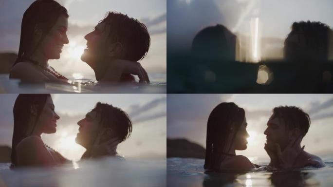 浪漫的异性恋夫妇在美丽的金色日落时在海里游泳。接吻和拥抱在一起