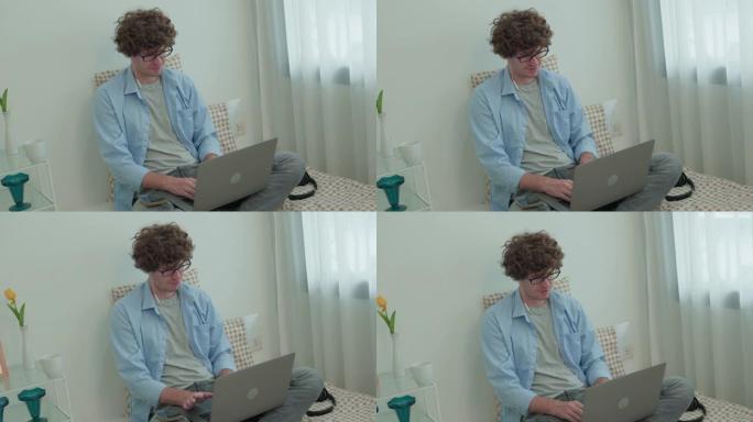 年轻人在家工作，在看着带耳机的屏幕笔记本电脑时，带着微笑的脸坐在床上。