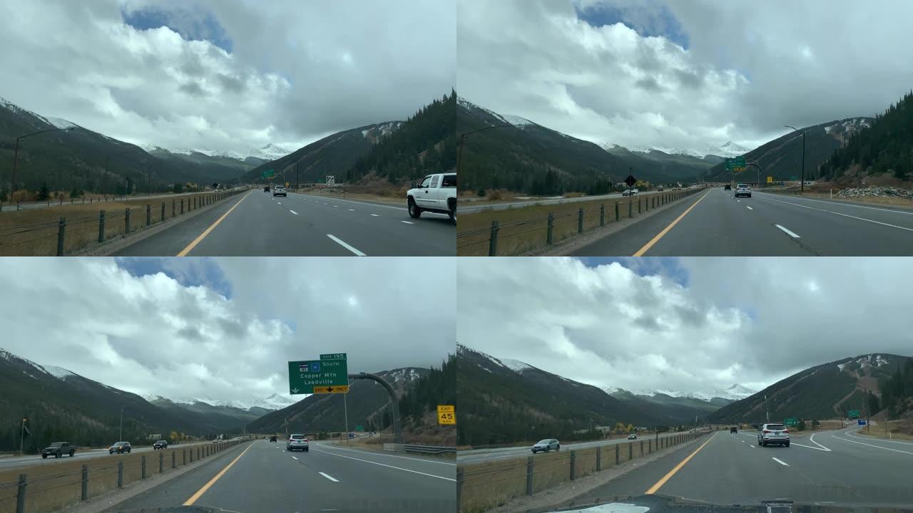 驾驶员的观点在秋天沿着铜山Leadville出口的70号州际公路在雨中行驶，阳光明媚的秋天会变色树木