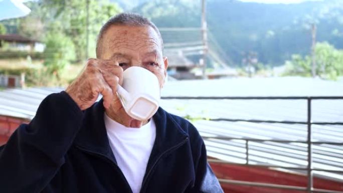亚洲老人在家独自喝茶放松。