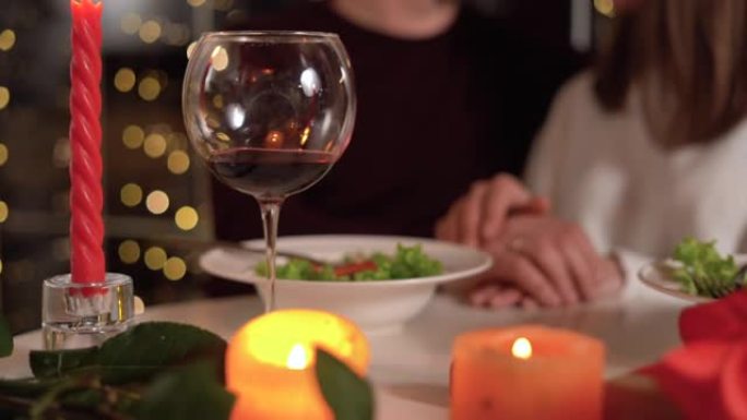 恋爱中的情侣牵着浪漫的晚餐约会，情人节，周年纪念日。烛光晚餐，爱