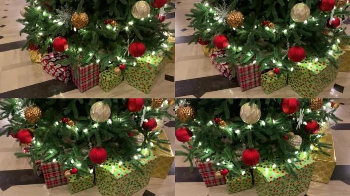 酒店大堂美丽的圣诞树，下面包裹着明亮的礼物，节日装饰品和悬挂在树枝上的清晰圣诞灯