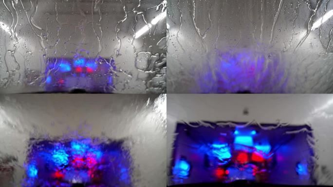 当汽车在洗车场冲洗并驶入干燥区域时，您可以透过汽车的挡风玻璃看。水滴在挡风玻璃上移动。
