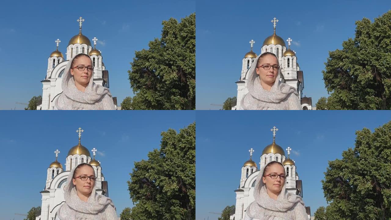 俄罗斯东正教徒戴围巾的中年妇女站在东正教会的背景上