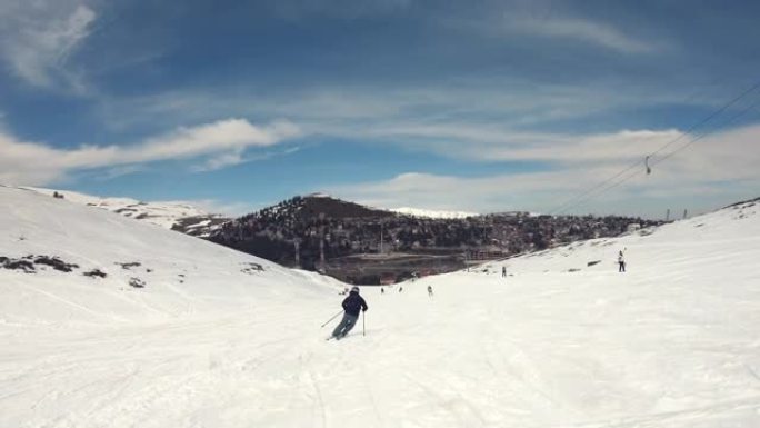 熟练的滑雪者在滑雪假期期间，在阳光明媚的寒假日子里，在欧洲阿尔卑斯山高高的蓝天上，在滑雪坡上进行长距