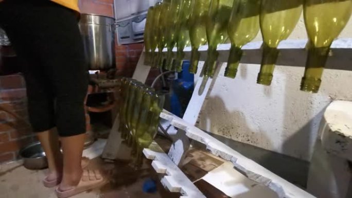 女人在沸水中烫伤一个酒瓶以进行巴氏杀菌，然后在当地一家小型酿酒厂工作时将其放在木架上