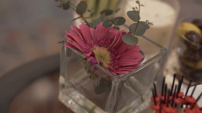 桌子上摆着鲜花和一些带有开胃菜的小吃的玻璃花瓶的特写镜头
