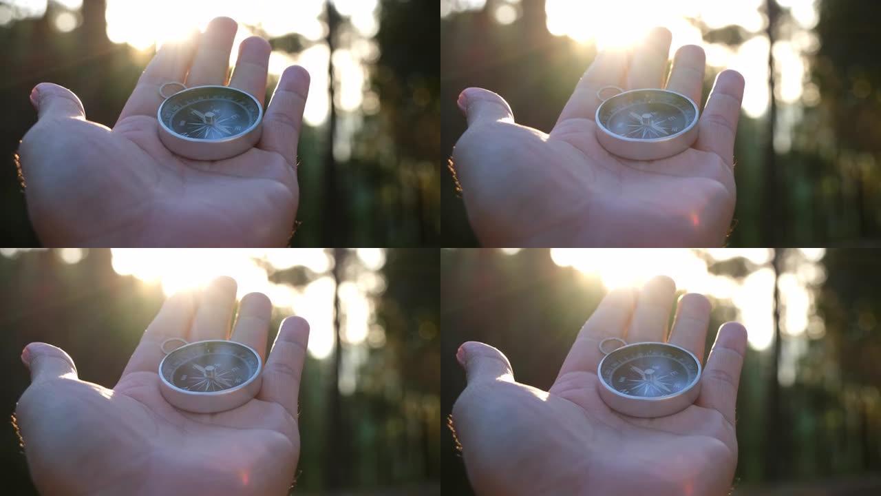 手握指南针在天然松林背景上。森林景观中的手握指南针。年轻的旅行者在夏季山区用指南针寻找方向。